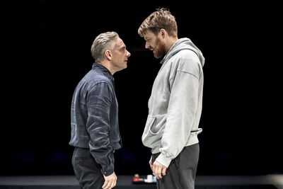 Two men stand opposite each other, looking at one another.