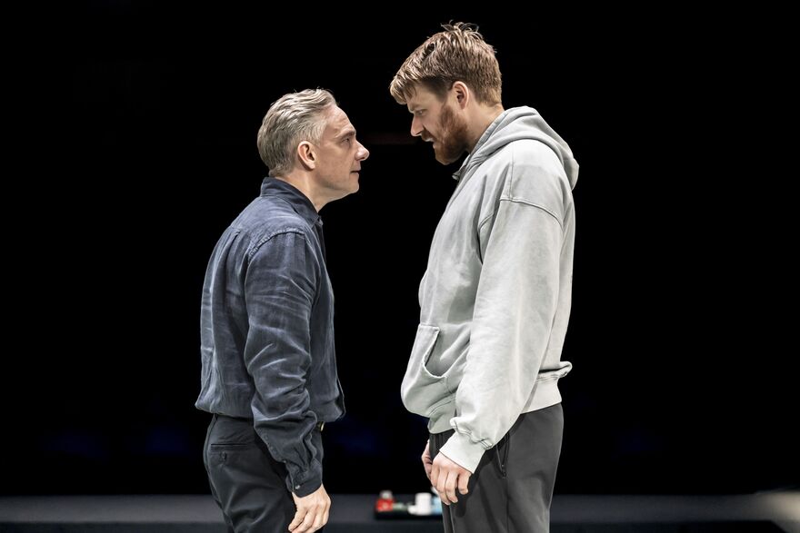Two men stand opposite each other, looking at one another.