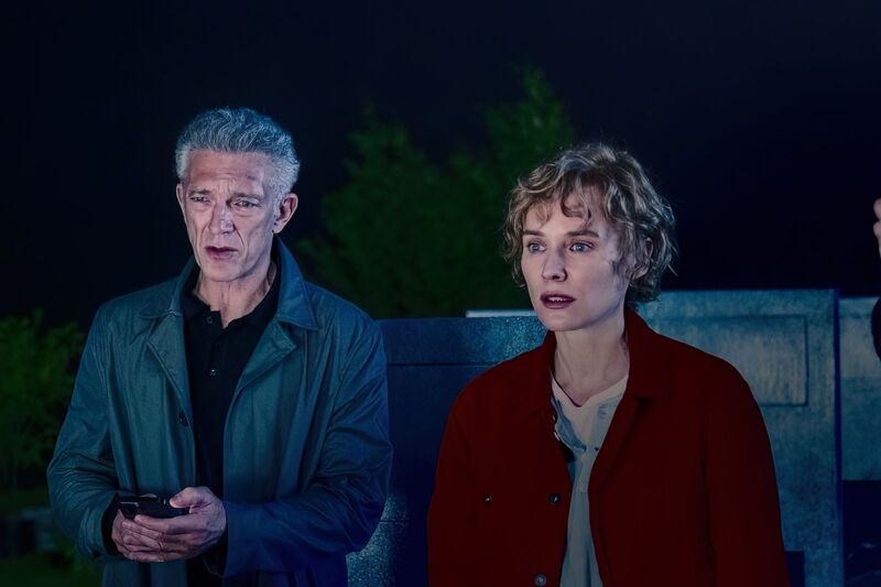An older man and a younger woman stand outside at night.