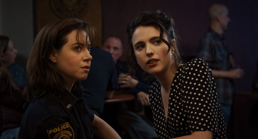Aubrey Plaza and Margaret Qualley talk together in a bar.