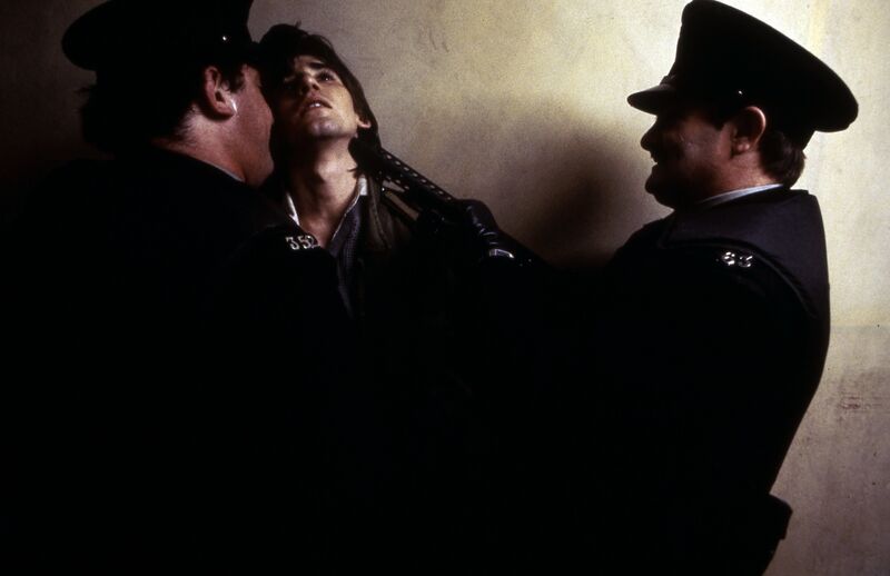 A man is restrained by two police officers.