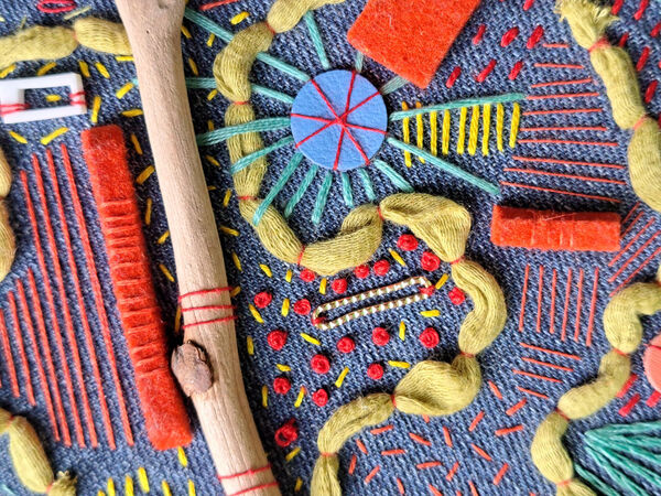 Close up of a stitched artwork with different stitches, colours and adornments