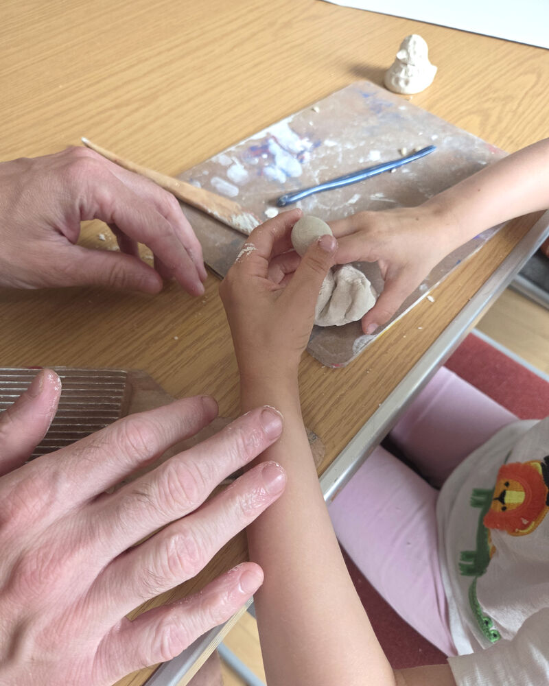 An adult and a child hands doing a clay actvity