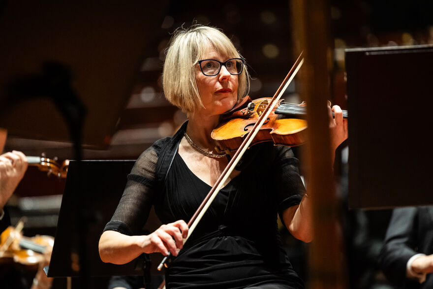 A photo of a lady with glasses and bobbed hair plays the violine