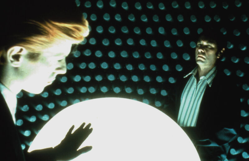Two men in a soundproofed room stand in front of a glowing dome
