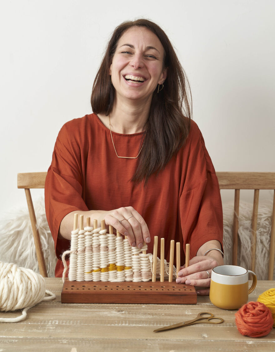 Stephanie Fradette smiling while doing peg loom weaving