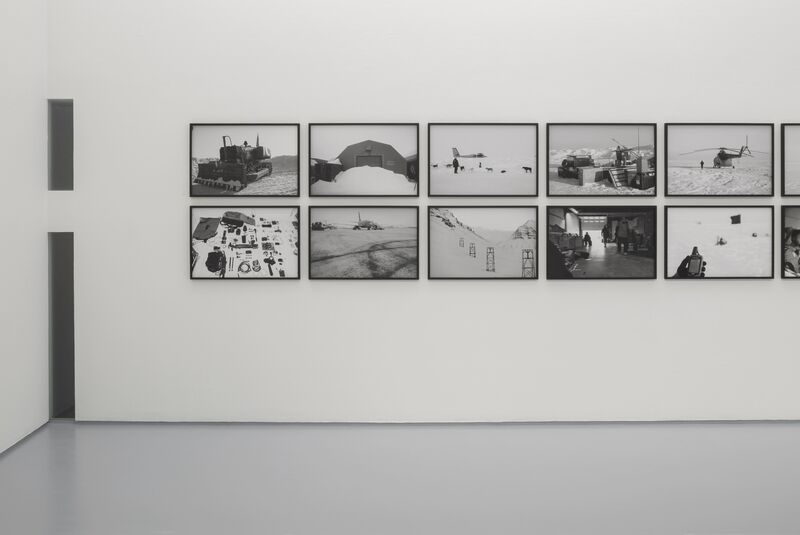 From Santiago Sierra's exhibition, Black Flag. A polar expedition is documented in black-and-white photography, which has been framed and placed on a white gallery wall.