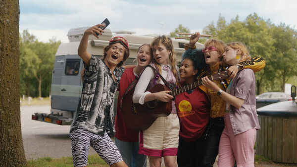 A group of teens pose for a selfie with a guitar and drumsticks 