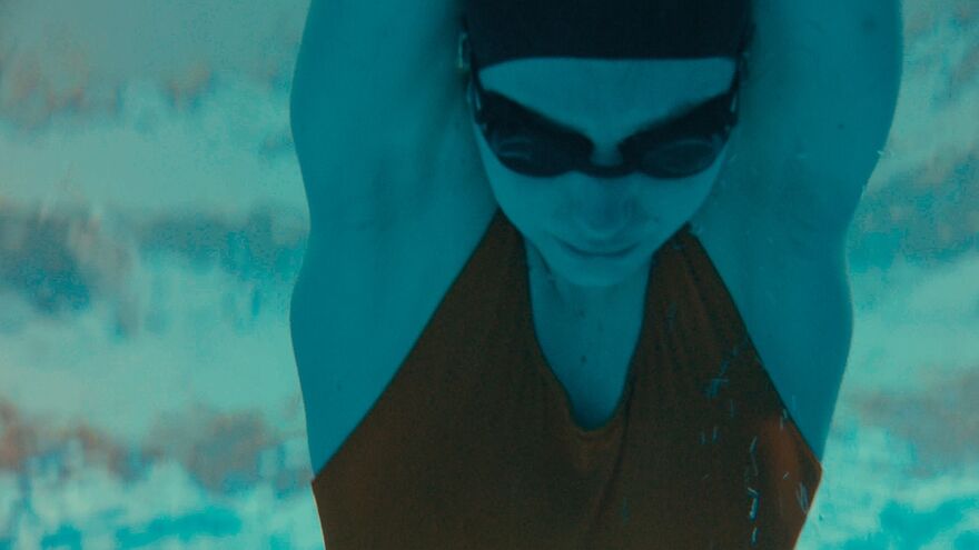 A person wearing a swimming hat and goggles dives under water