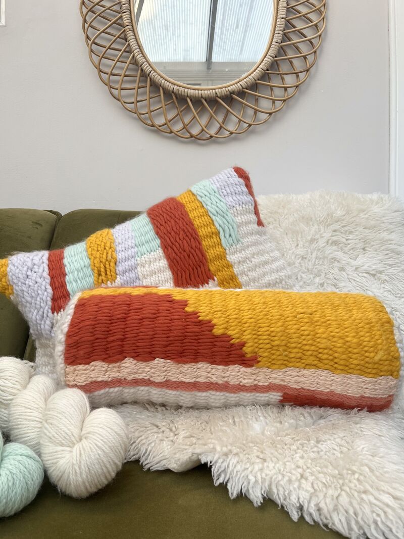 Cushion and bolster cushion on a sofa with yarn and a sheep skin rug