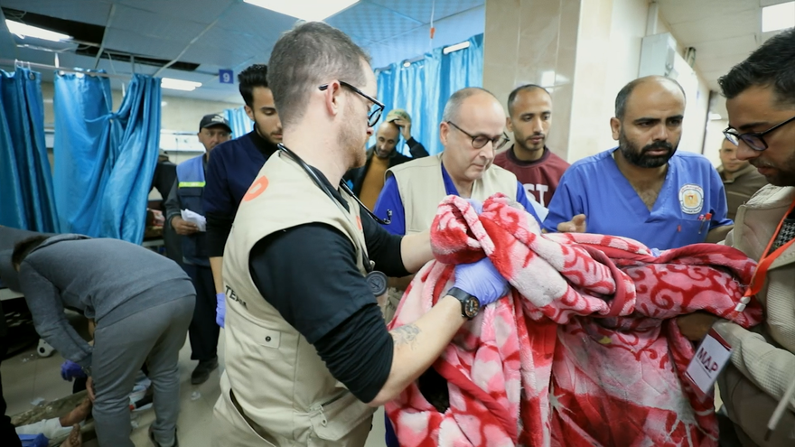 Doctors lifting an injured child in a blanket