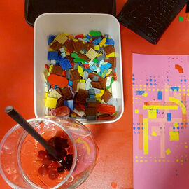 Drink, box of lego dots and a print on a table in Create Space