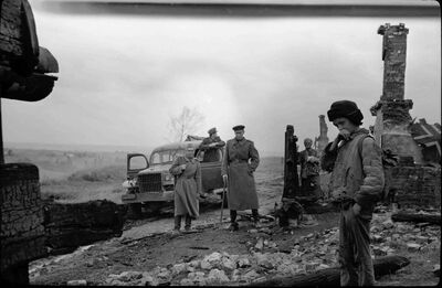 World War 2 soldiers look at a bombed house, a boy watches on.