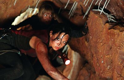 Two women walking through a cave with a torch