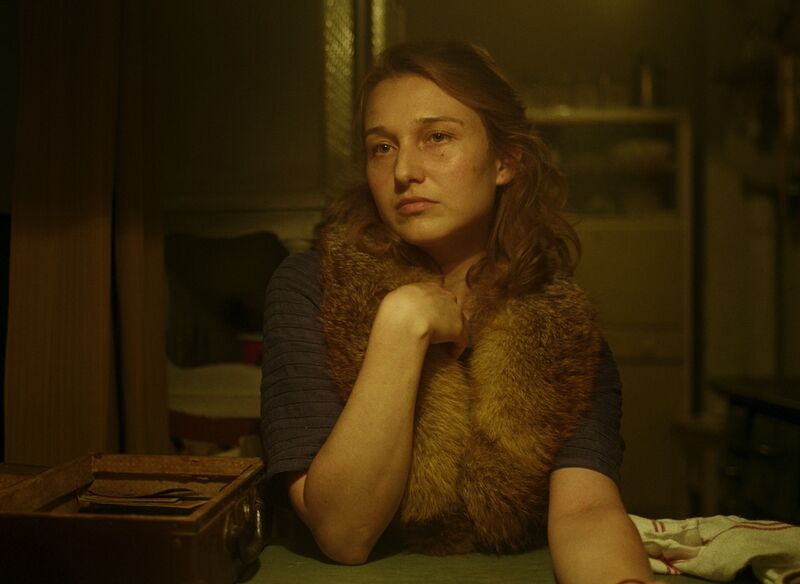 A woman in a fur wrap sits at a table