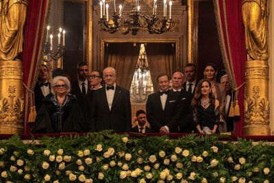 A group of dignitaries stand on a gilded balcony.