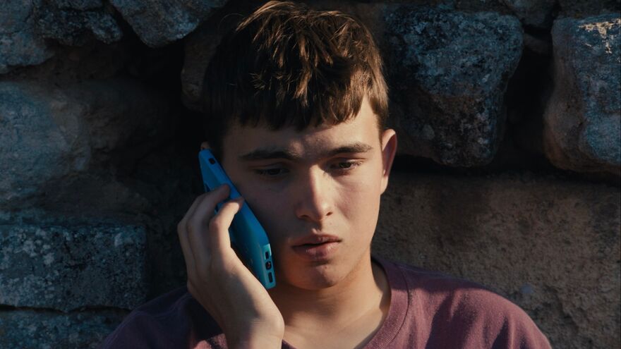 A young man on a phone, standing outdoors
