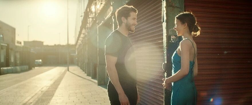 A young man and woman talk to each other on an empty commercial street on a sunny day.