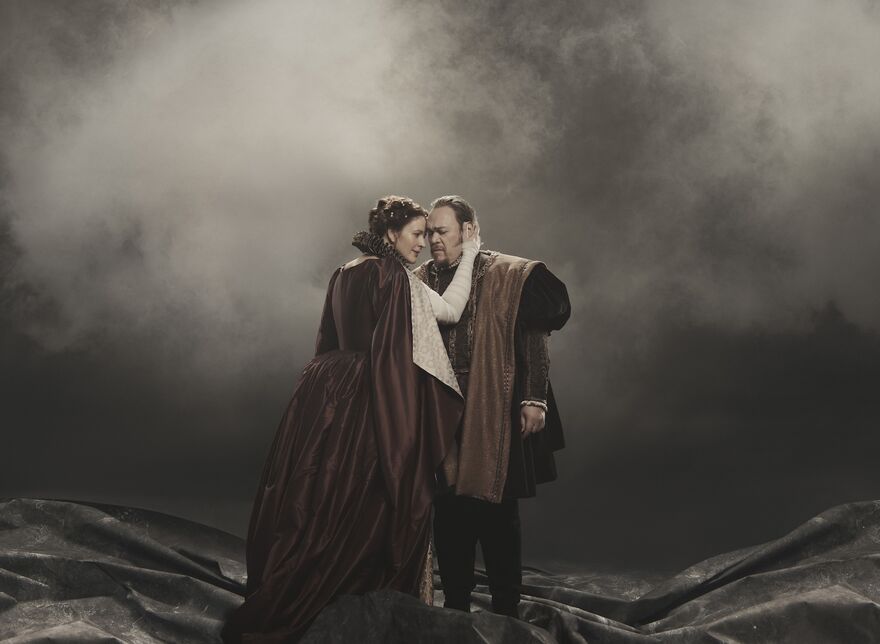 A man and woman embrace on stage in Macbeth