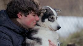 A teenage boy and a husky puppy.