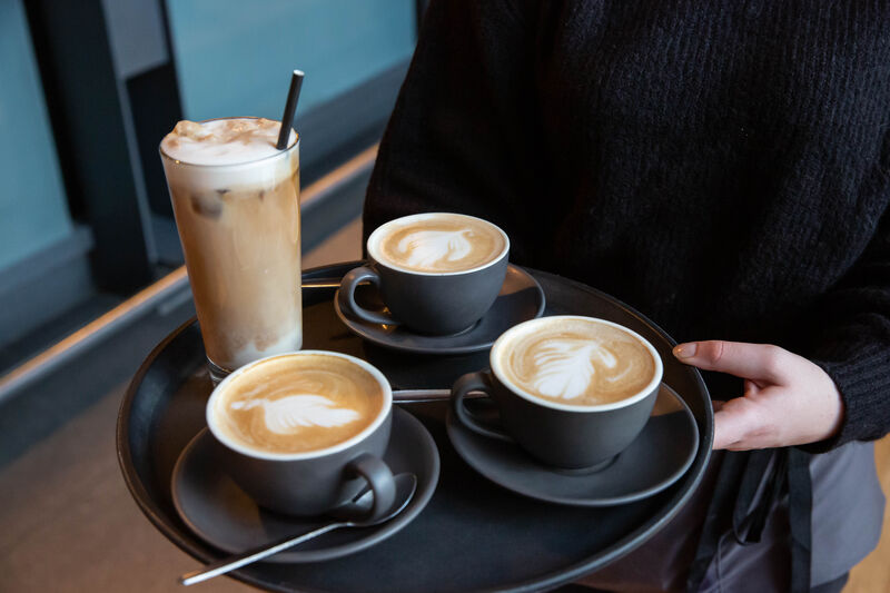 Person carrying a tray of coffees