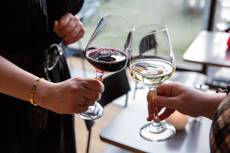 Close-up of two people clincking together wine glasses