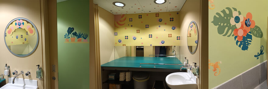 Our Infant Changing Space, decorated with paintings of flowers and green walls.