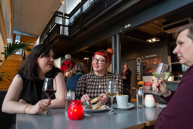 Three peole around a table in Jute Cafe Bar enjoying drinks and food