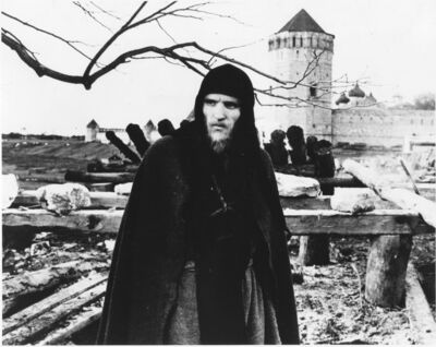 A man in a black clock stands by a Russian fortification