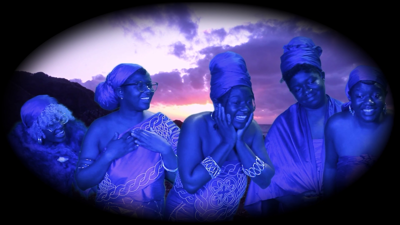five women in traditional dress look happily towards the right corner. They are bathed in blue light and the image is in a oval shape