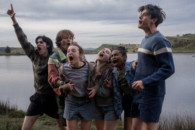 A group of teens pose joyfully by a loch