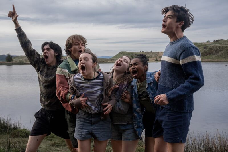A group of teens pose joyfully by a loch