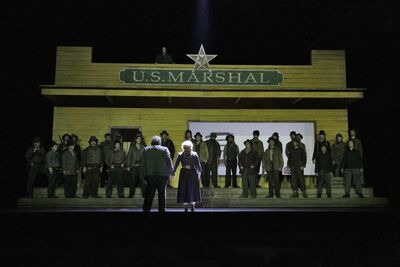 Opera stage filled with singers in western costume.