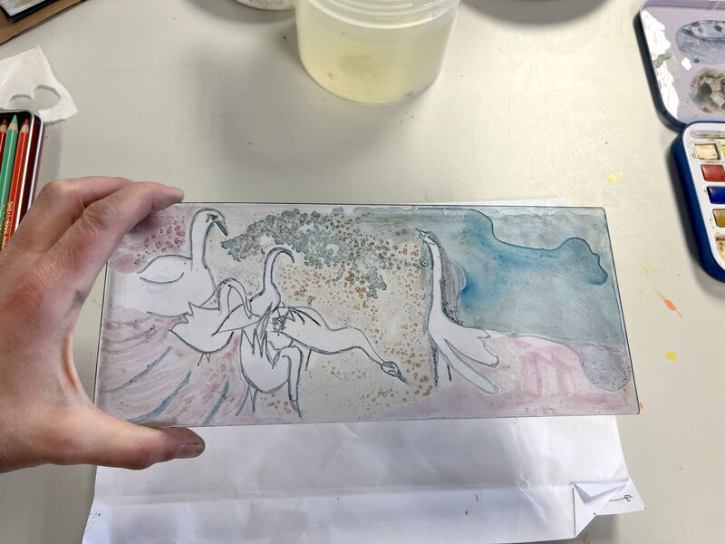 Person holding a perspex plate with a scene of birds painted in watercolour