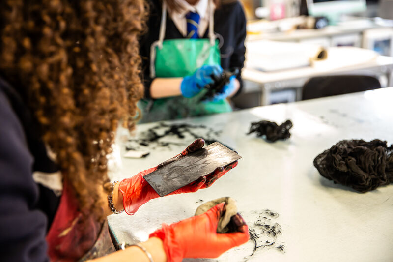 Morgan Academy pupil wiping an etching plate while wearing orange gloves
