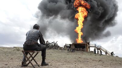 A man watches flames from an oil well.