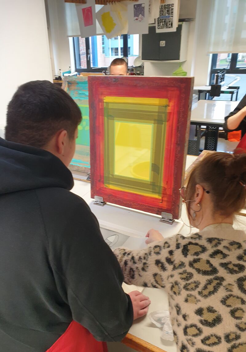 Artist tutor helping a pupil to screen print