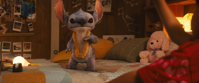 Fluffy alien Stitch stands on a child's bed