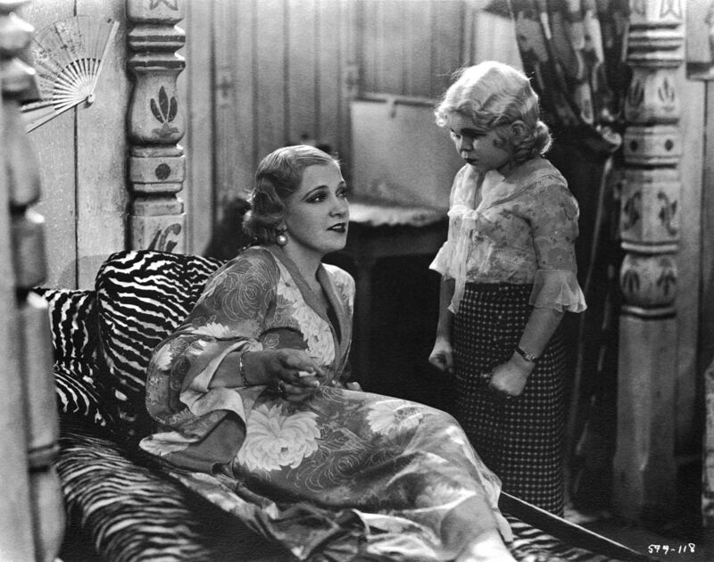 A black and white image of a women with 20s style lying on a zebra chaise longe 