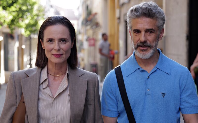 A smartly dressed woman and a man in a summer shirt walk towards the camera