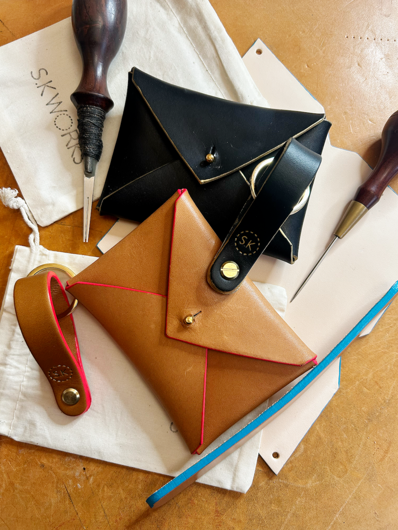 Leather purses and keyrings surrounded by tools