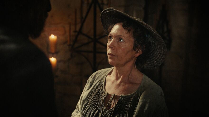Olivia Colman looks up at a figure to her left