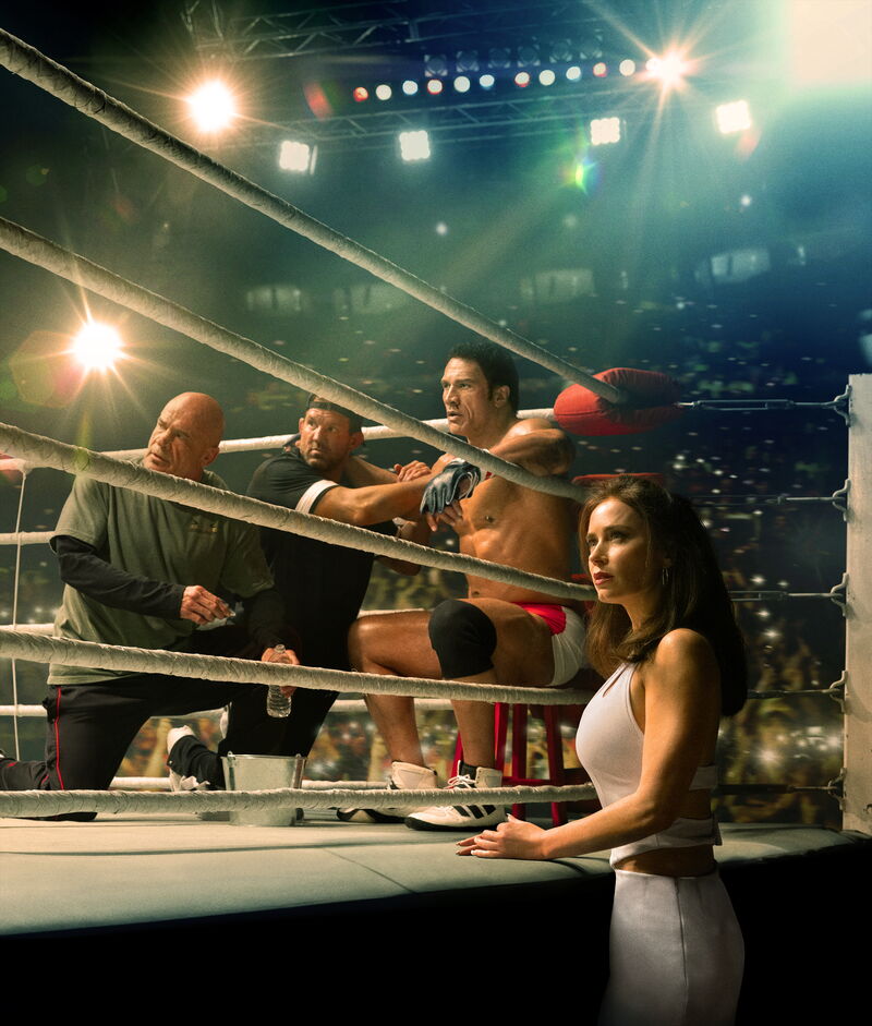  An MMA fighter sits in a boxing ring with his coaches next to him.