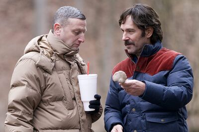 Two men wearing winter coats stand outside looking at a bone.