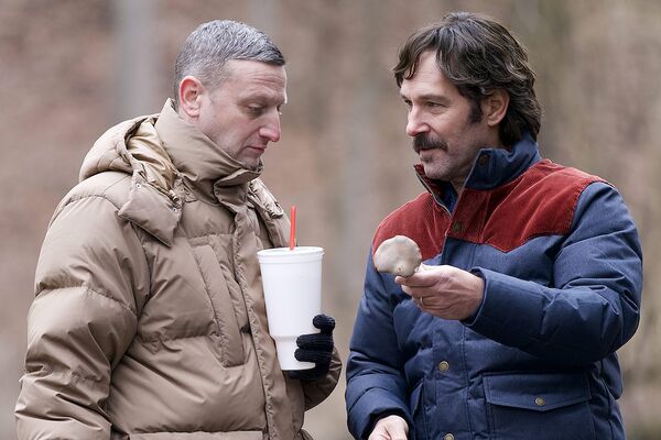 Two men wearing winter coats stand outside looking at a bone.