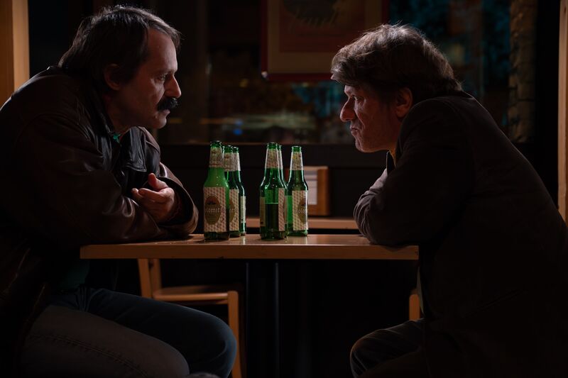 Two men at a table with beer bottles