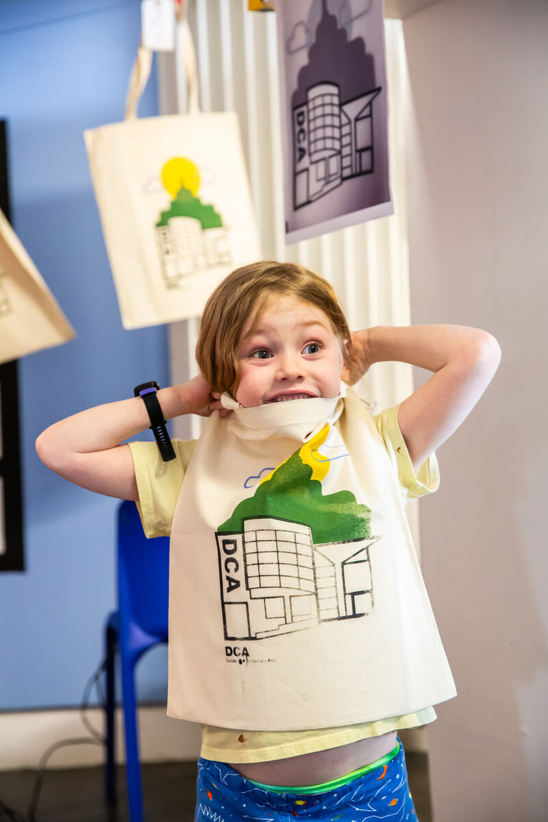 Child looking happy holding a tote bag with a print of DCA on it