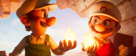 Mario and Luigi hold flames and smile together in a still from the Super Mario Galaxy Movie