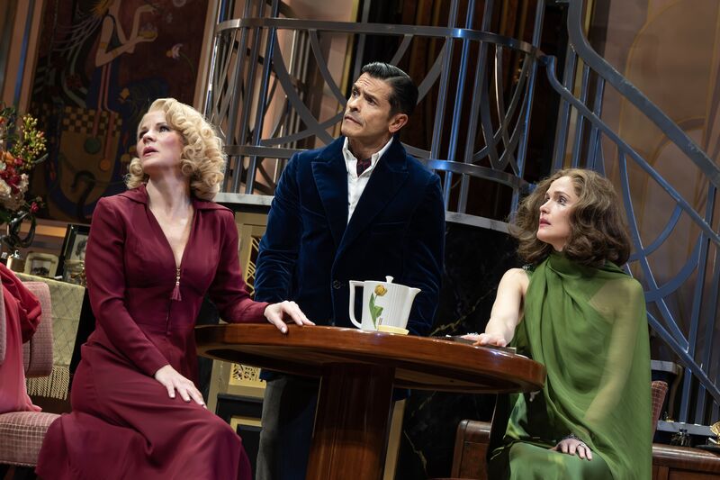 Two women and a man around a table, look concerned 