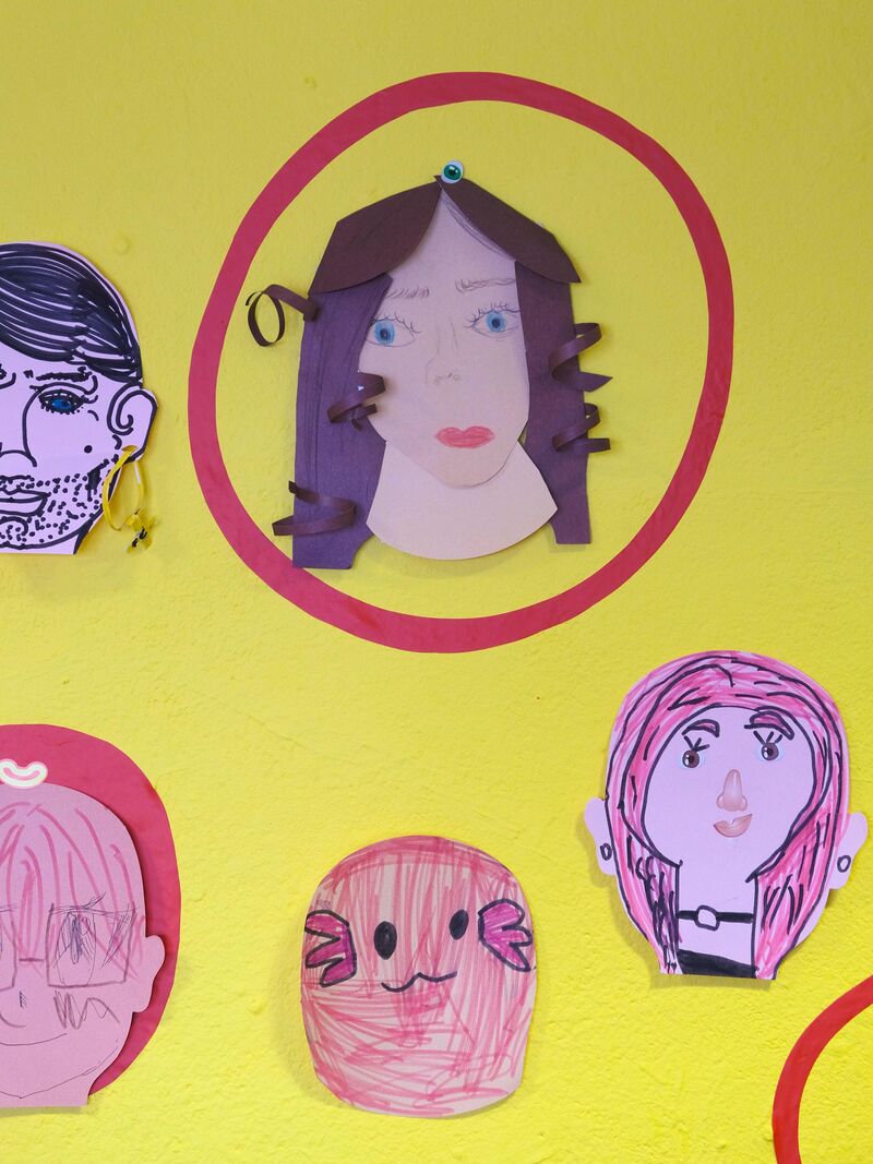 Paper portraits on a yellow wall